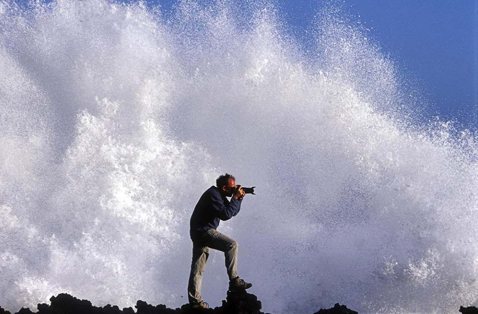 Фотограф у Атлантического океана на Ла Пальма, Канарские острова, Испания. Рассказывает фотограф Карлос Виргили Райб: «Мы фотографировали на следующий день после крупного шторма. Я увидел этот утес, о который каждые 30 секунд разбивались волны. Я попросил друга попозировать для «мокрой фотографии». Спустя несколько снимков нам все же удалось «зацепить» большую волну». (Carlos Virgili Ribe, Nature's Best Photography)