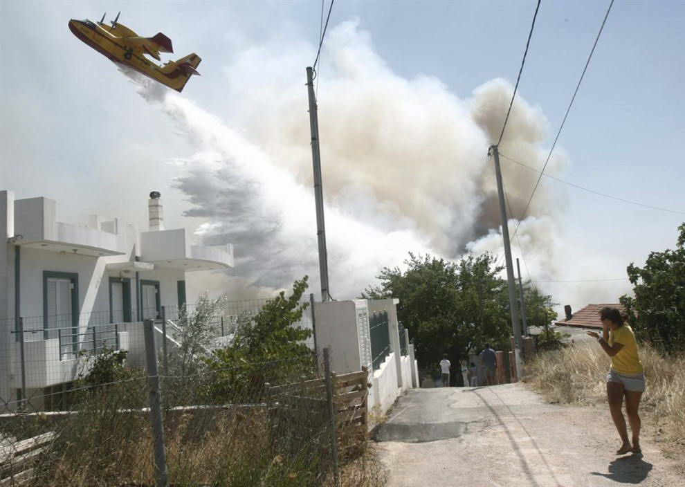 Пожарный самолет сбрасывает тонны воды на лесной пожар в деревне Варнава к северо-востоку от Афин в субботу. (Yiorgos Karahalis/Reuters)
