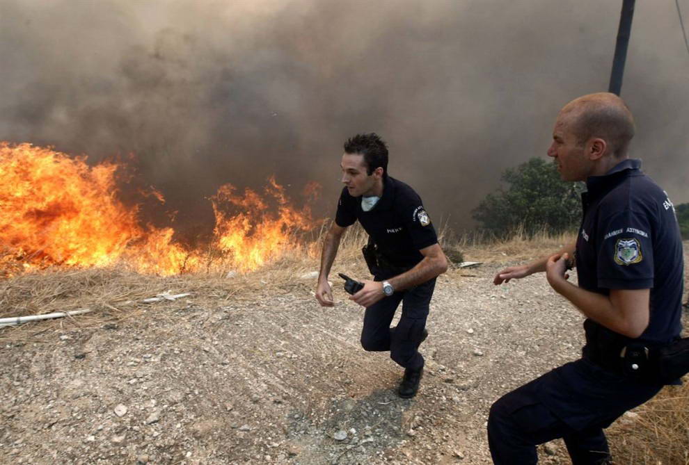 Полицейские бегут от огня в деревне Варнава. (Yiorgos Karahalis/Reuters)