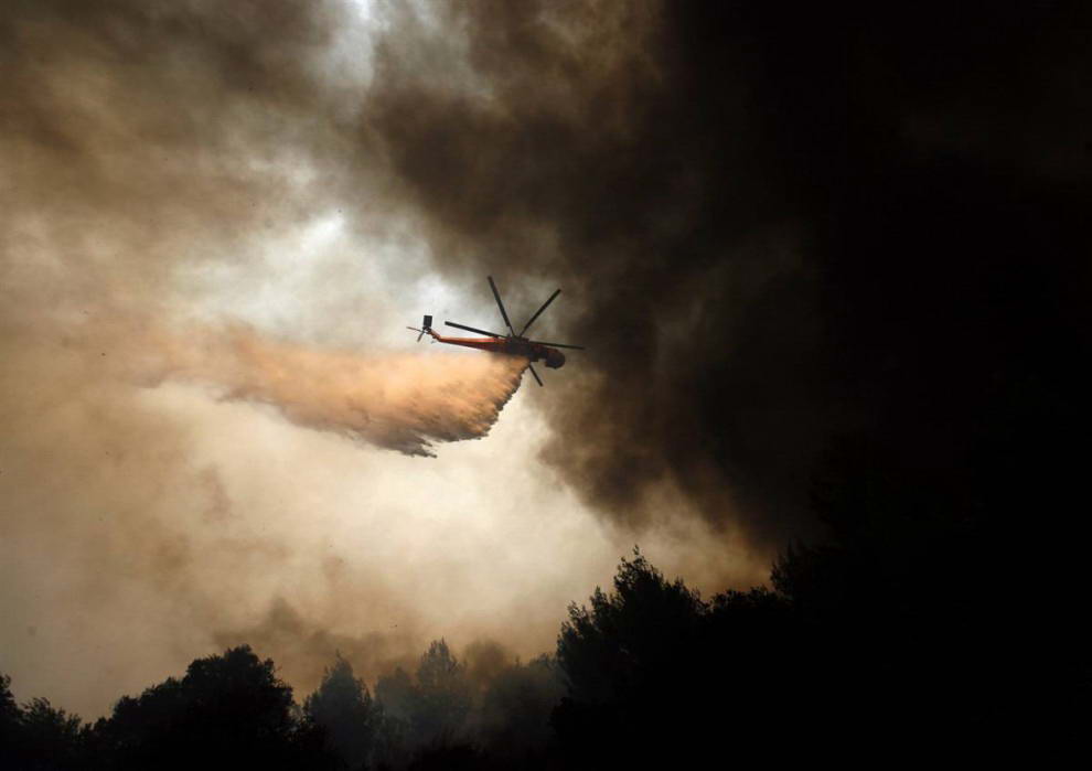 Вертолет сбрасывает воду на пожар возле деревни Марафон. (Dimitri Messinis/AP)