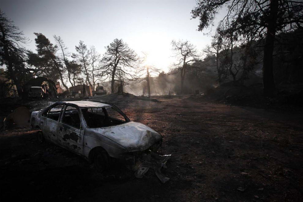 Сожженный автомобиль в Агиос Стефанос в понедельник. Пожарные и самолеты вступили сегодня в битву с лесными пожарами, рвущимися к Афинам, по просьбе напуганных жителей. (Angelos Tzortzinis/AFP - Getty Images)