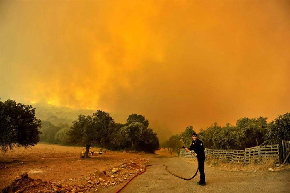 Пожарный ждет помощи во время пожара, ворвавшегося в деревню Калетци к северу от Афин в субботу. (Aris Messinis/AFP - Getty Images)