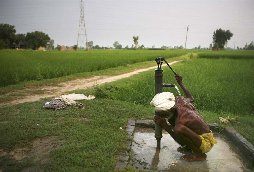 Пожилой крестьянин купается под ручной колонкой у деревенской дороги на севере Индии, где с 1960-х годов наблюдается огромное увеличение уровня использования воды. Частично это связано с ростом населения, но еще больше с так называемой "зеленой революцией", благодаря которой в Индии резко возросло сельскохозяйственное производство, и, как следствие, увеличилось потребление подземных вод для орошения. (Altaf Qadri/AP)