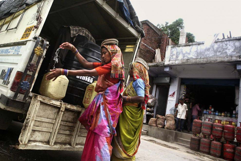 Работница моет руки перед тем, как начать разгружать баки с водой из грузовика на стройплощадке в северной Индии. Проблема нехватки воды в Индии стала серьезной политической проблемой. Проблема эта касается всех классов общества: от жителей элитных кварталов, где регулярно случаются перебои с водой, до бедных крестьян, которые остро нуждаются в воде для поливки, чтобы вырастить урожай. (Altaf Qadri/AP)