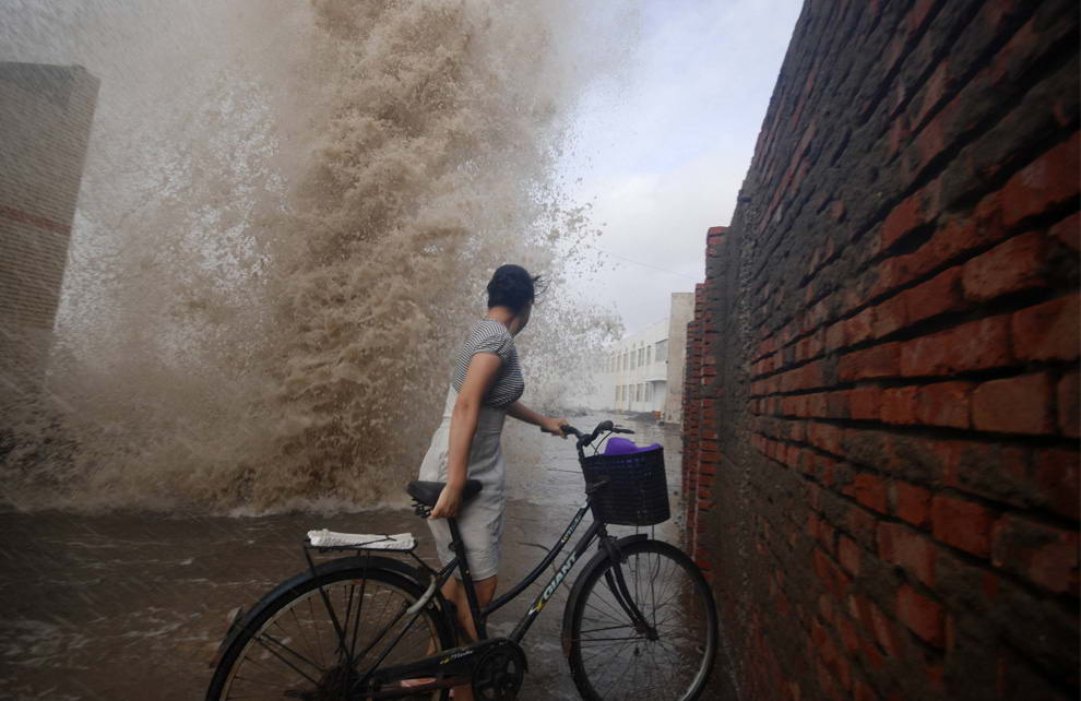 Женщина смотрит на разбивающиеся о берег волны, вызванные тайфуном Моракот. Снимок сделан в городе Венлинг, китайской провинции Чжэцзян 7 августа 2009 года. (REUTERS/China Daily)