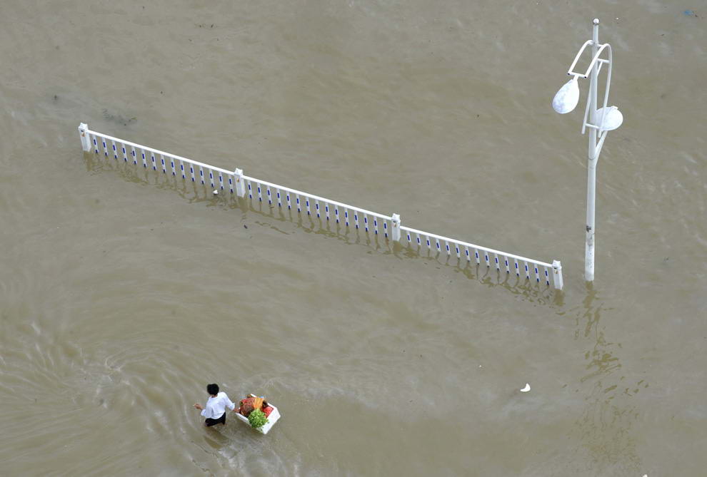 Житель тащит по залитой улице коробку с овощами после того, как тайфун Моракот достиг провинции Чжэцзян в Китае 10 августа 2009 года. (REUTERS/Lang Lang)