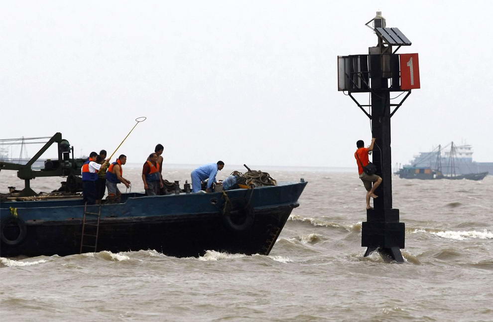 Спасатели пытаются достать человека, попавшего в ловушку, когда тайфун Моракот приблизился к Шанхаю, Китай, 9 августа 2009 года. (REUTERS/Stringer)