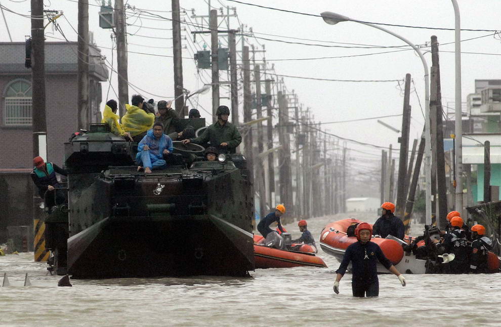 Эвакуированные жители сидят на крыше военного транспорта, пока спасатели прочесывают затопленный район в поисках выживших. Тайфун Моракот принес в Чиатунь, округ Пиндун в южном Тайване серию проливных дождей, вызвавших наводнение 9 августа 2009 года. (PATRICK LIN/AFP/Getty Images)