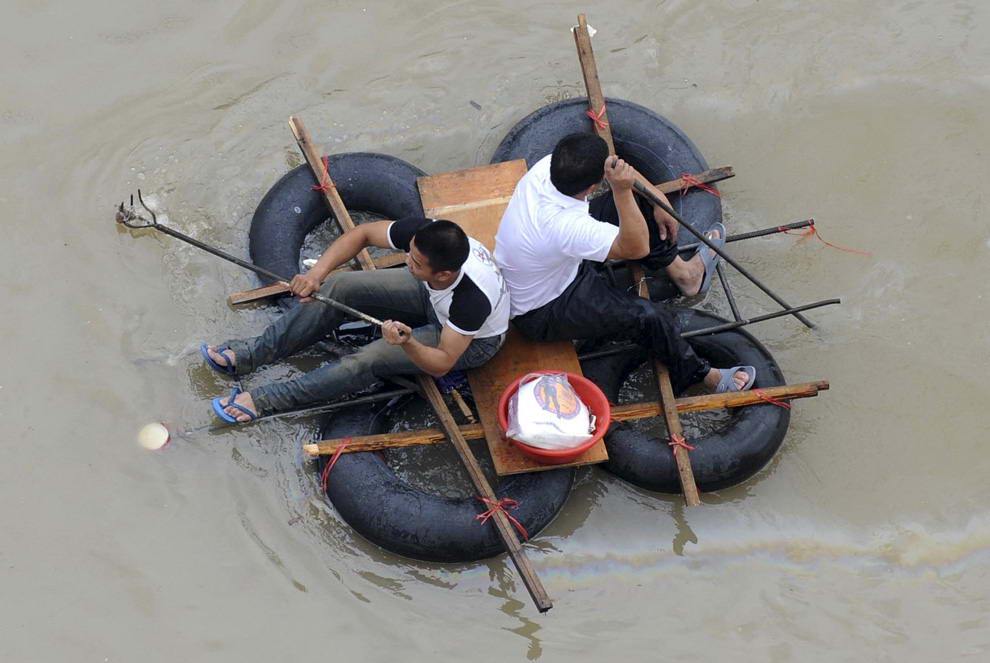 Жители проплывают по затопленной улице на самодельном плоту после того, как тайфун Моракот достиг Вэньчжоу, провинция Чжэцзян, Китай, 10 августа 2009. (REUTERS/Lang Lang)