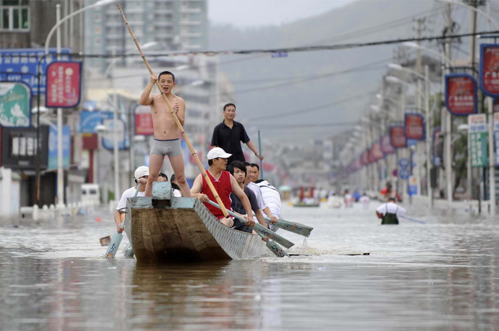 Люди плывут на лодке по затопленному району в округе Цаньнань на востоке Китайской провинции Чжэцзян в понедельник 10 августа 2009. (AP Photo)