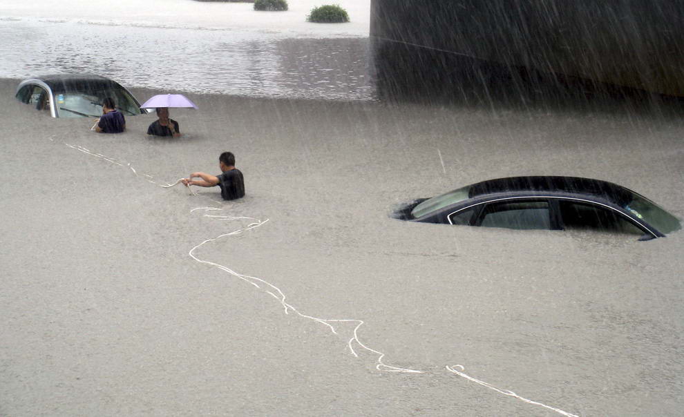 Спасатели пытаются вытащить из воды застрявшую машину. Снимок сделан в городе Вэньчжоу, провинция Чжэцзян, Китай, 9 августа 2009. (REUTERS/China Daily)