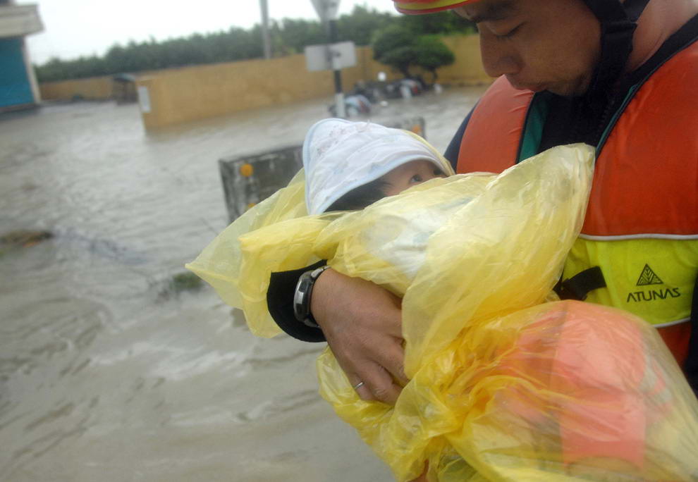 Мужчина несет младенца, во время спасения семьи от наводнения, возникшего из-за тайфуна Моракот в Чиатуне, округ Пиндун, южный Тайвань 9 августа 2009. (PATRICK LIN/AFP/Getty Images)