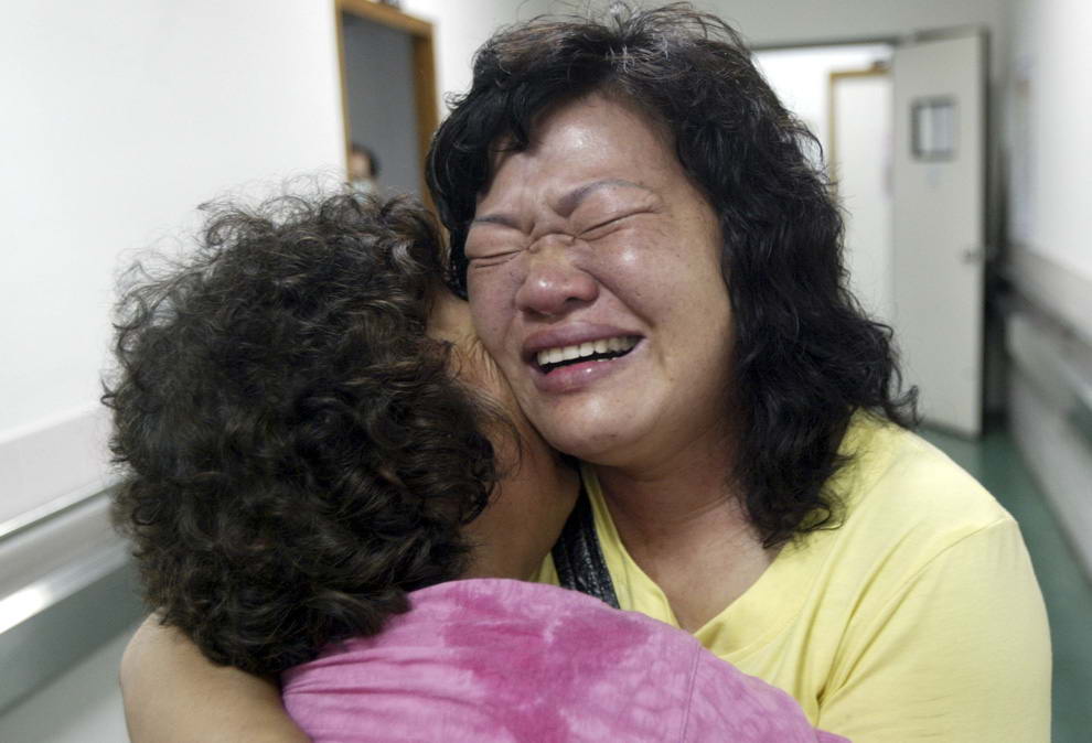 Две женщины обнимаются в местном пункте спасения после того, как спасательный вертолет доставил их из деревни, почти разрушенной оползнями от тайфуна Моракот в округе Гаосюн, южный Тайвань, понедельник 10 августа 2009. (AP Photo)