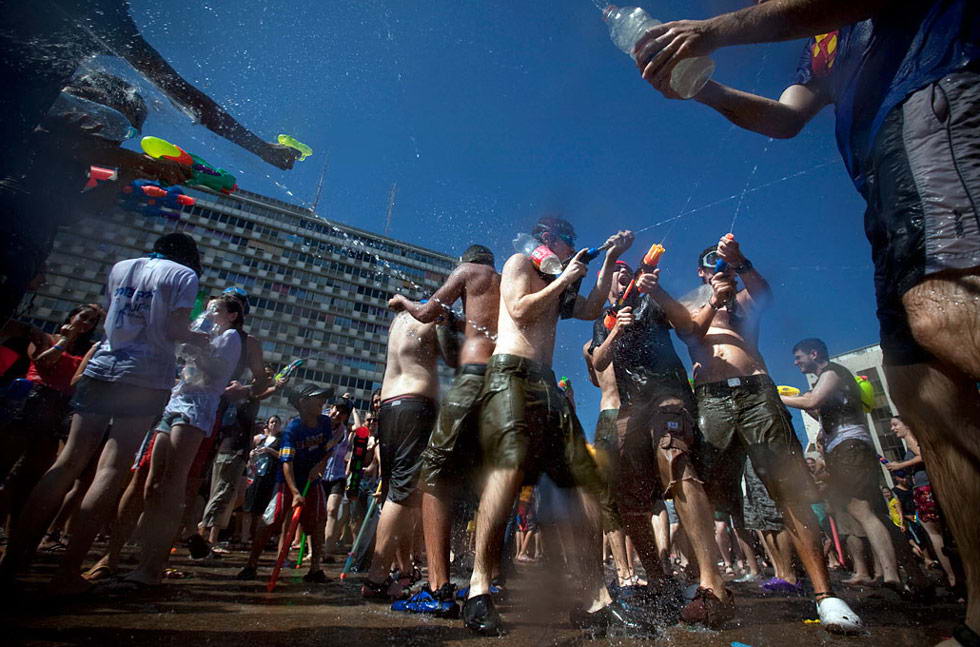 Израильтяне брызгаются водой во время ежегодной водяной битвы на площади Рабин в Тель-Авиве 3 июля. (Oded Balilty/AP)