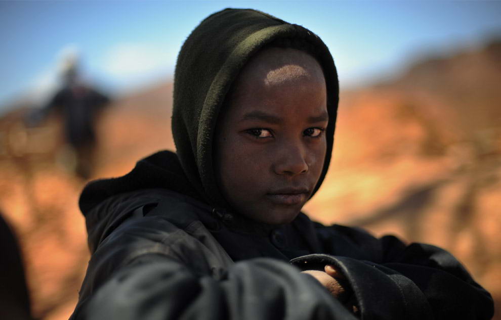 13-ти летний Донне сидит около своего отца, пока тот готовит кофе во время перерыва от добычи сапфиров в Анзанакаро на Мадагаскаре.