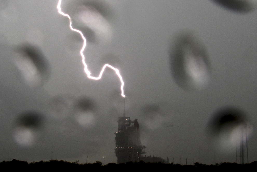 Молния ударяет в башню у космического шаттла Endeavour, который стоит на вершине стартовой площадке 39А во время грозы в Космическом центре Кеннеди на мысе Канаверал, штат Флорида 10 июля 2009. NASA отменили попытку запуска шаттла 11 июля 2009 для того, чтобы оценить возможный ущерб от удара молнии. (REUTERS/Gene Blevins)