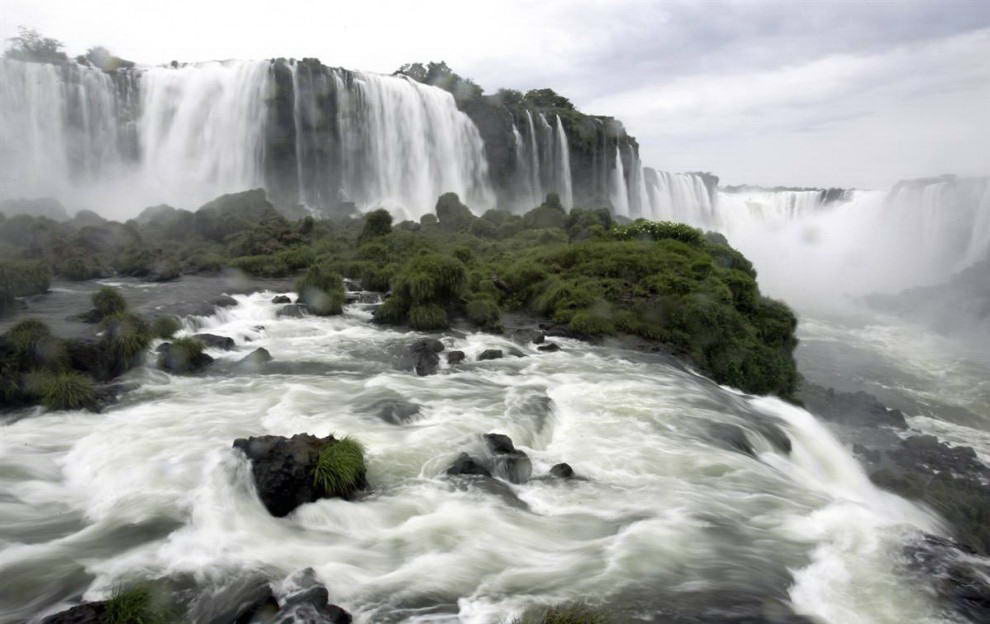 Расположенный на границы Бразилии и Аргентины водопад Игуасу является одним из самых протяженных каскадов водопадов в мире. Его длина составляет около 2 миль. «Глотка дъявола» (справа) - самый высокий среди водопадов. Игуасу с двух сторон окружен Национальными парками с тропическими джунглями. (Juan Mabromata / AFP - Getty Images)