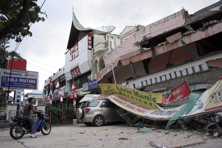 Человек садится на мотоцикл у рухнувшего торгового центра после землетрясения в Паданге, на острове Суматра в Индонезии.