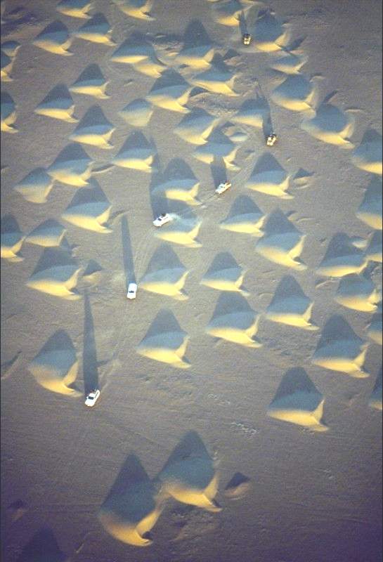 Грузовики, проносящиеся через песчаные дюны в пустыне Аль-Ар-Руб-Хали, известной также как Пустая четверть мира, на Аравийском полуострове. (George Steinmetz) 