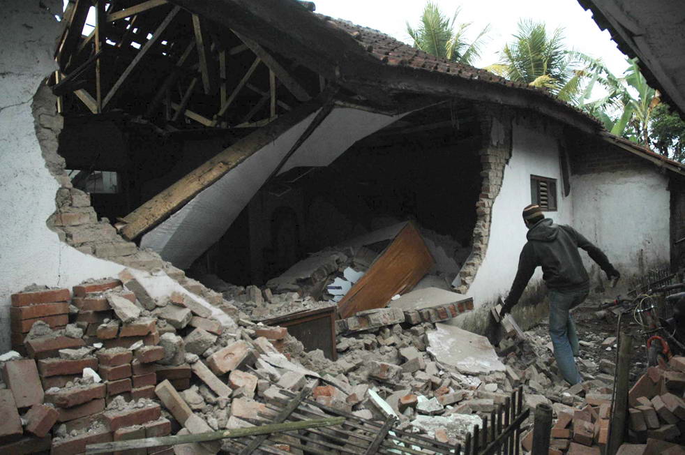 Местный житель осматривает руины разрушенного землетрясением дома в Tasikmalaya, Западная Ява, Индонезия, в четверг, 3 сентября. Спасатели голыми руками прорывают завалы из камней и мусора в поисках десятков жителей деревни, которых погребло под завалами вызванными землетрясением в 7 баллов. (AP/Hade Rupa)