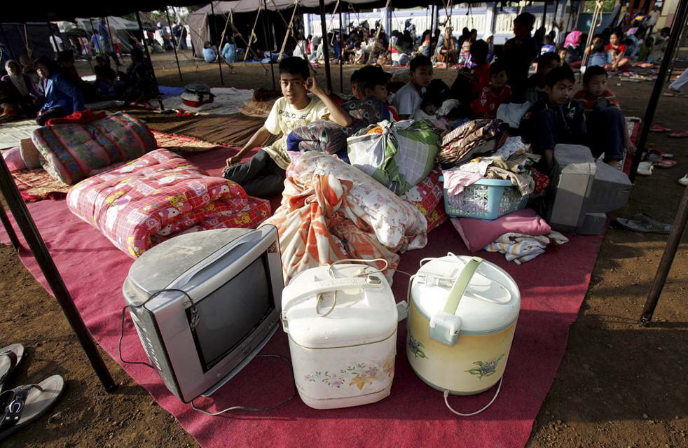 Индонезийские юноши, лишившиеся крова из-за землетрясения, сидят среди своих вещей во временном жилье в Tasikmalaya, Западная Ява, Индонезия, в четверг, 3 сентября. (AP/Pikiran Rakyat Daily)