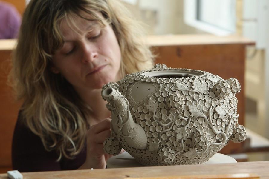 Художница работает над изысканным чайником на заводе по производству мейсенского фарфора в Германии.