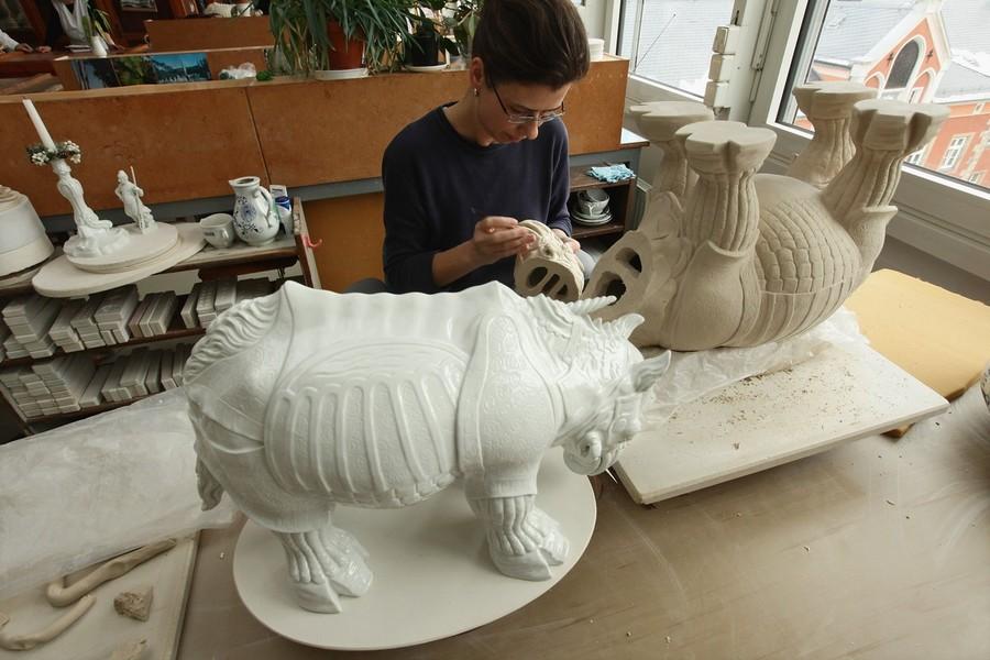 Художница работает над изысканной статуэткой носорога из фарфора.