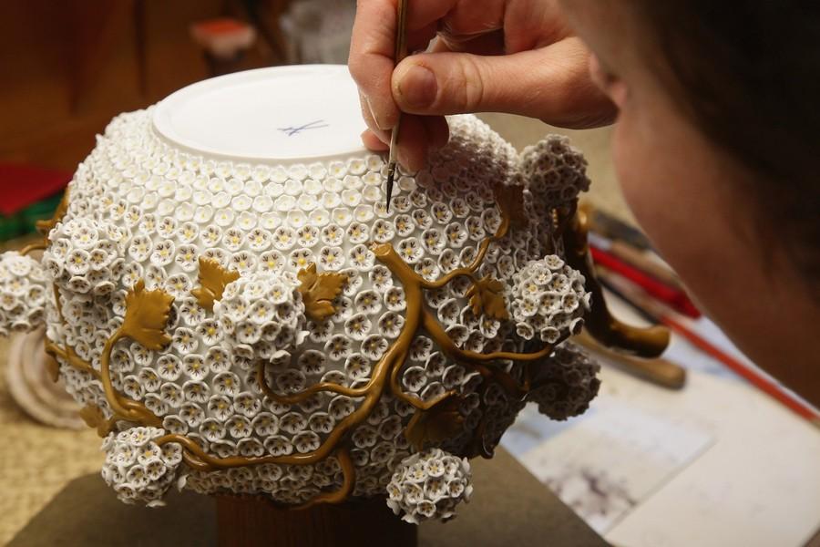 Ремесленник Рамона Кестель рисует крошечные цветочные лепестки на замысловатом декоративном чайнике.