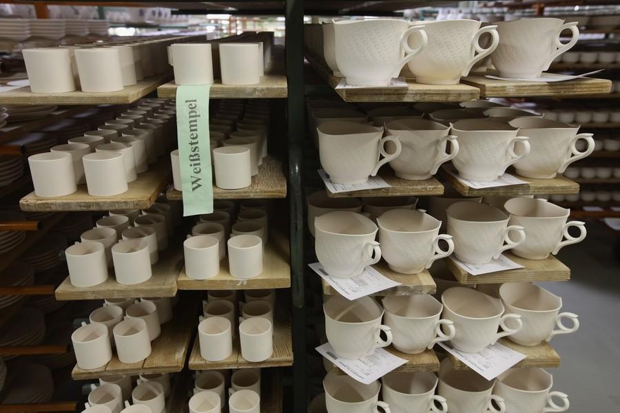 Фарфоровые чашки на полпути к своему конечному состоянию на деревянных поддонах на заводе фарфора в Мейсене.