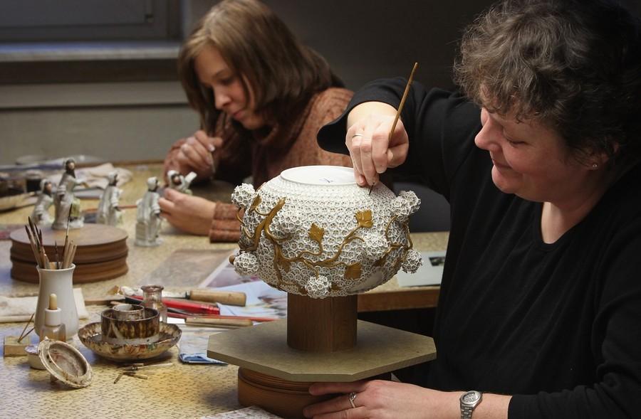Ремесленница Рамона Кестель рисует крошечные лепестки на декоративном чайнике.