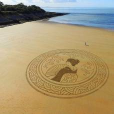Художник создает огромные рисунки из пляжного песка