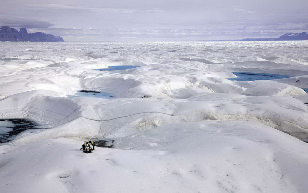 Ученый Джейсон Бокс из государственного университета Огайо и эксперт полярной экспедиции Эрик Филипс (оба члены Гринпис) с помощью экспертов в области полярной логистики устанавливают камеру для покадровой съемки 16-километрового ледника Петерманна в северо-восточной части Гренландии 29 июля 2009 года. Корабль организации Гринпис «Арктический рассвет» прибыл в этот район на несколько недель для проведения научных исследований в области изменения климата, а также для наблюдения за разрушением ледника. (NICK COBBING/AFP/Getty Images)