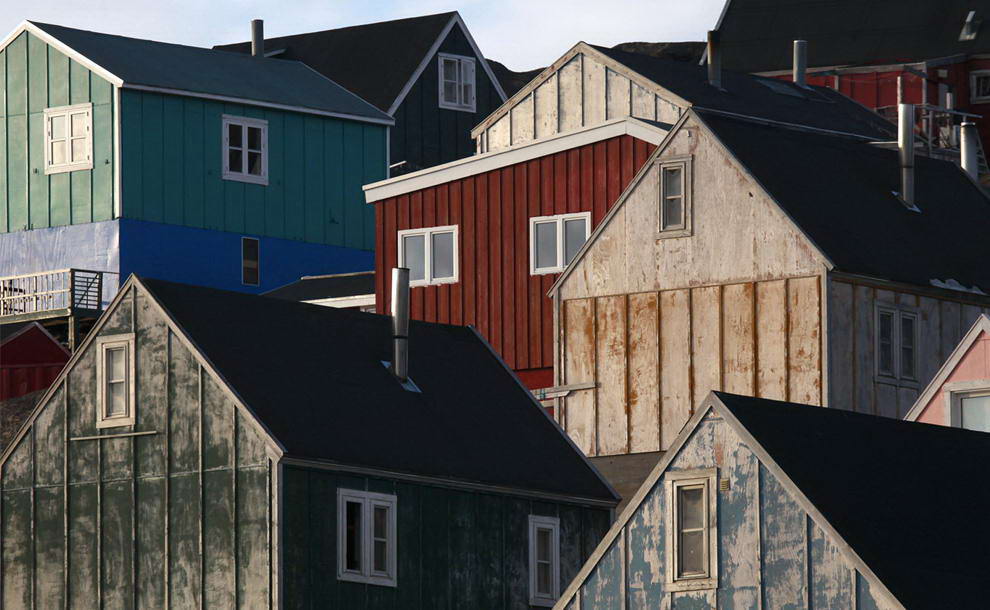 Дома освещаются ранним солнцем в городе Тасиилак в восточной Гренландии 4 августа 2009 года. (REUTERS/Bob Strong)