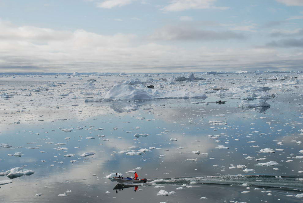 Рыбачья лодка разрезает воды ледникового гренландского фьорда Илулиссат в котором полно айсбергов 3 июля 2009 года. (Slim ALLAGUI/AFP/Getty Images)