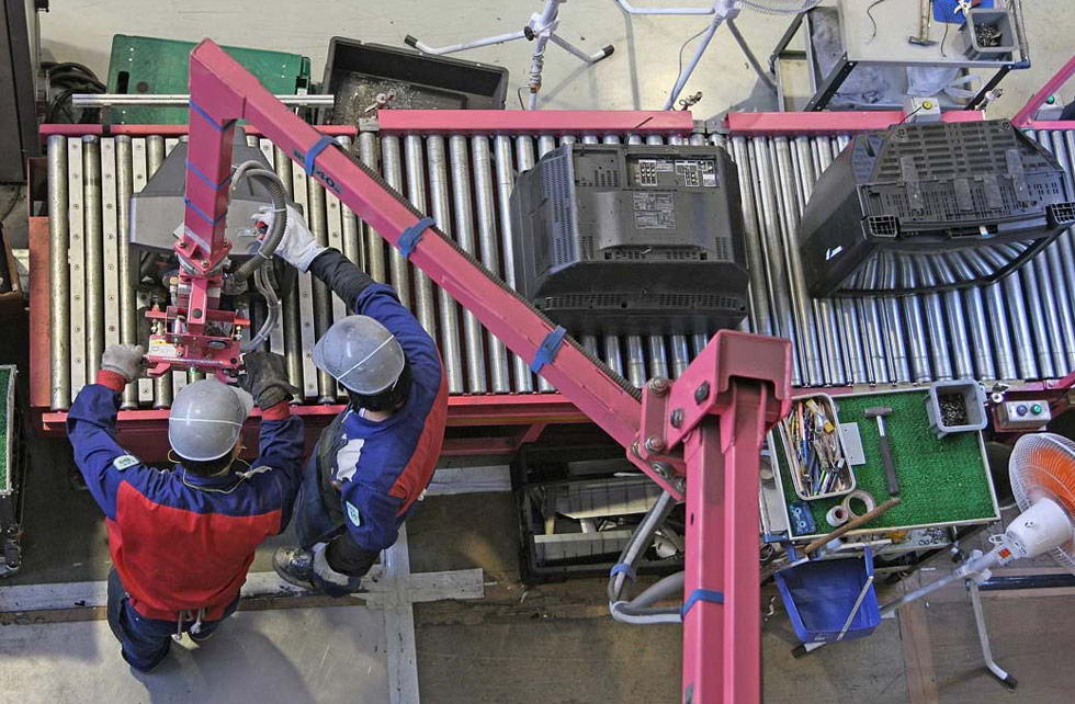 Рабочие помещают телевизор на конвейер во время процесса переработки в центре компании Panasonic Eco Technology в Японии 2 июля. В этом центре ежегодно разбирается около 700 000 телевизоров, кондиционеров, стиральных машин и холодильников, и 90% этих продуктов перерабатывается. (Junko Kimura/Getty Images)