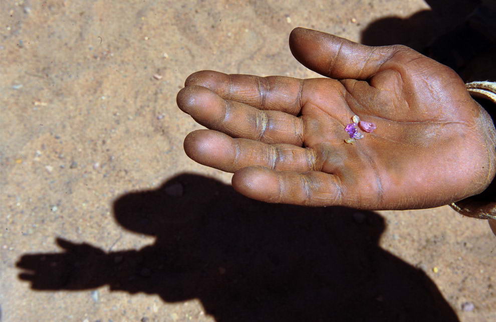 Дьедонне Лаха демонстрирует драгоценные камни, которые он вместе с другими старателями добыл за два дня, копая землю и промывая гравий в реке около деревни Анзакаро возле Илакаки.
