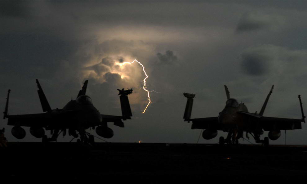 Молния между самолетами F/A-18C Hornet на полётной палубе авианосца «USS John C. Stennis» в Тихом океане 8 апреля 2009. (Mass Communication 2nd Class Elliott Fabrizio/U.S. Navy)