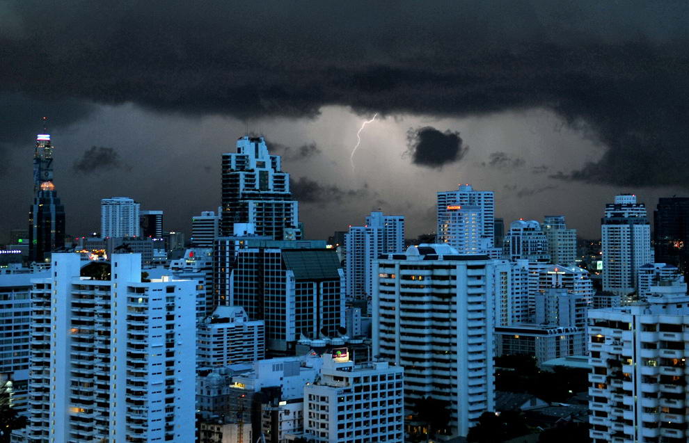 Молния освещает небо и отражается от поверхности зданий в Бангкоке 13 июня 2009. (NICOLAS ASFOURI/AFP/Getty Images)