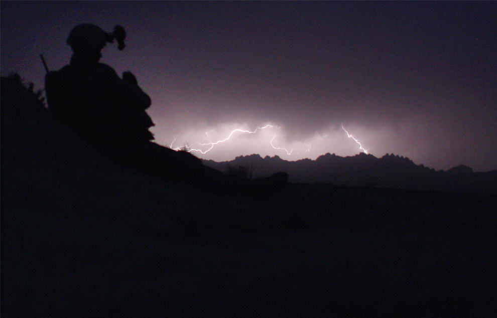 Американский морской пехотинец наблюдает за вспышками молний на горизонте во время операции по поиску талибов 25 марта 2009 году неподалеку от деревни Баква в отдаленных областях на юго-западе Афганистана. (John Moore/Getty Images)