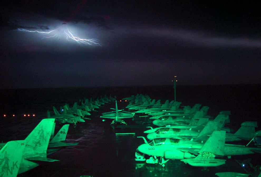 Снимок сделан в море на борту судна «Авраам Линкольн» 2 ноября 2002 года. Молния над горизонтом освещает полётную палубу. (Lt. Troy Wilcox/U.S. Navy)