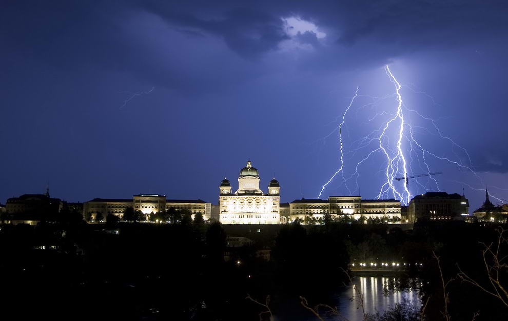 Молния освещает небо над Швейцарским Федеральным дворцом в Берне во время грозы 17 июля 2009. (REUTERS/Michael Buholzer)