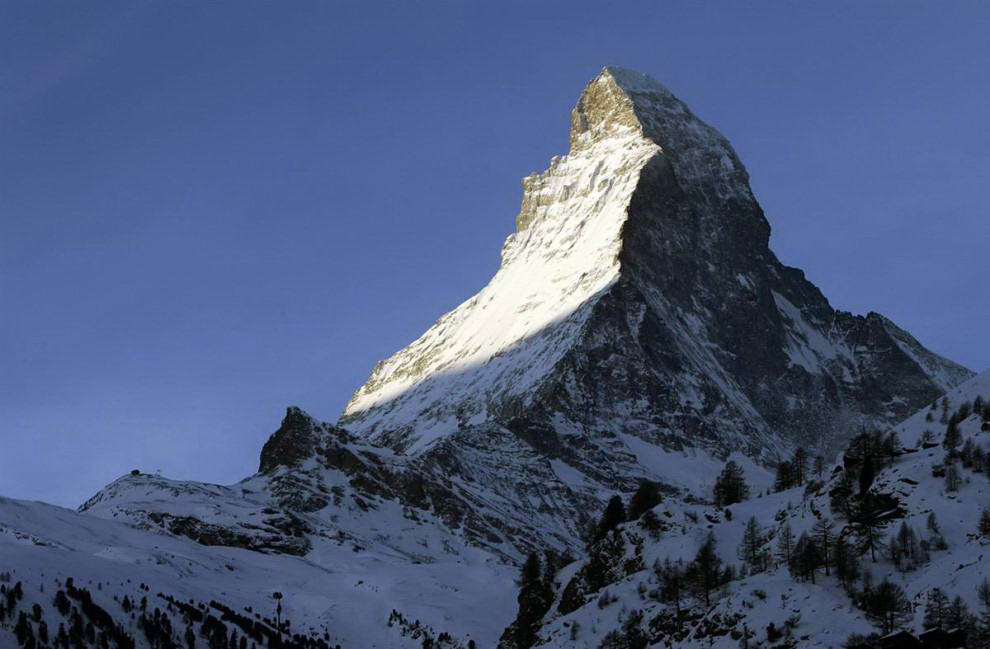 Гора Маттерхорн на границе Италии и Швейцарии не самая высокая (14,690 футов), но наверное самая впечатляющая. К ее вершине сходятся четыре треугольные грани и она принимает пирамидальную форму. (Olivier Maire / AP)