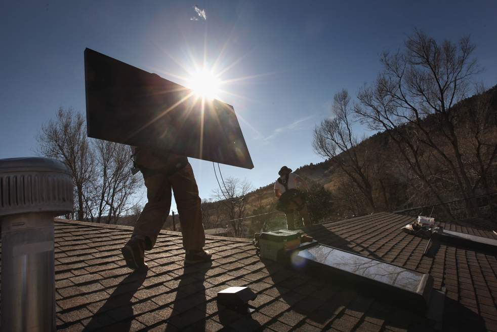Уэйд Эндрюс – работник компании «Namaste Solar» - несет солнечную панель на крыше жилого дома 4 марта в Болдере, штат Колорадо. Компании по выработке возобновляемой энергии (такие как  «Namaste») получат дополнительные фонды на создание «зеленых» инициатив из федерального пакета экономических стимулов. (Getty Images / John Moore)